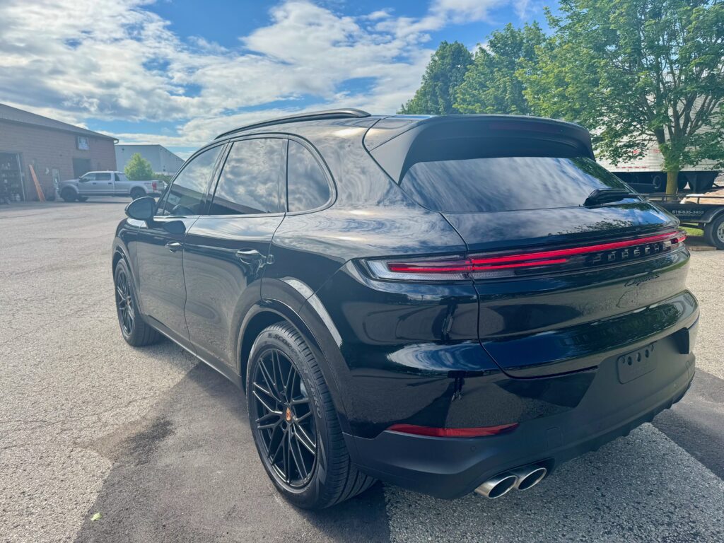 Rear three-quarter view of a black Porsche Cayenne after full body XPEL Ultimate Plus paint protection film installation.